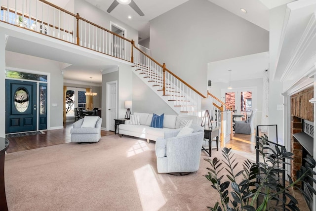 carpeted living room with wood finished floors, baseboards, a towering ceiling, and stairs