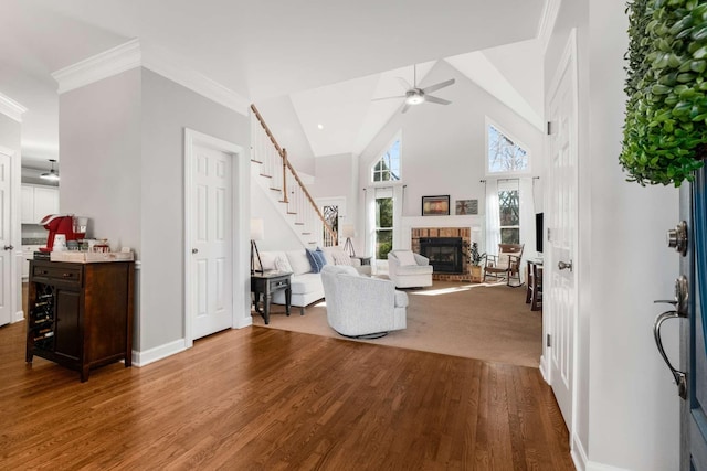 living room with high vaulted ceiling, wood finished floors, stairway, a brick fireplace, and ceiling fan