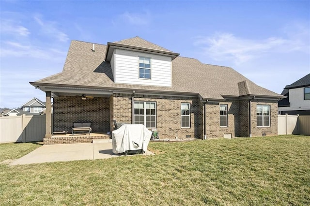 rear view of house featuring brick siding, fence private yard, a lawn, and a patio area