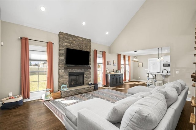 living room featuring dark wood finished floors, a fireplace, high vaulted ceiling, and baseboards