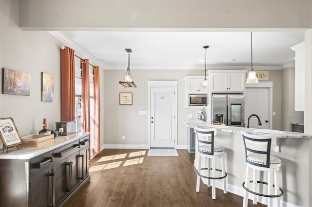 kitchen featuring a breakfast bar area, stainless steel appliances, crown molding, and dark wood-style flooring