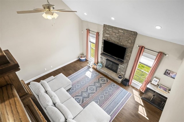 living room featuring ceiling fan, baseboards, wood finished floors, and a fireplace