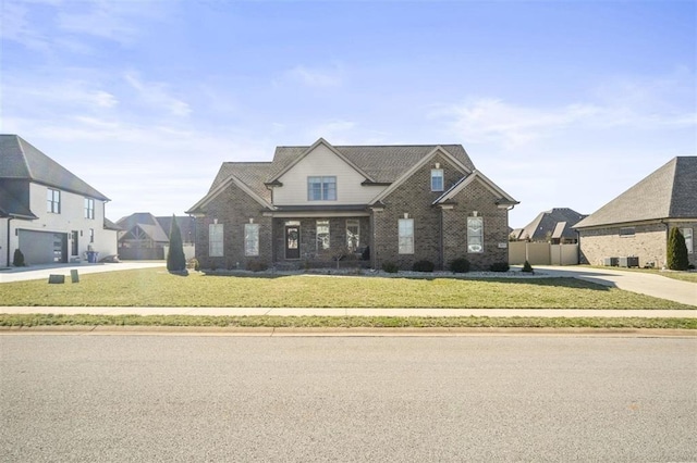 view of front of property with a front lawn, fence, and brick siding