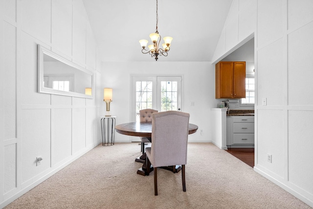 carpeted dining space featuring lofted ceiling, a decorative wall, and a healthy amount of sunlight