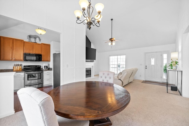 dining room with light colored carpet, a fireplace with flush hearth, high vaulted ceiling, and ceiling fan