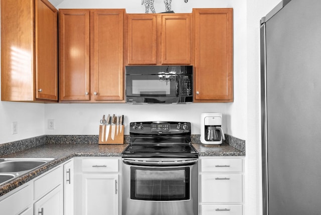 kitchen with a sink, dark countertops, white cabinets, and stainless steel appliances