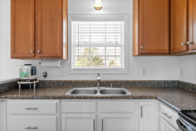 kitchen featuring white cabinetry, dark countertops, and a sink