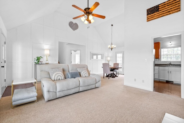 living room featuring ceiling fan with notable chandelier, high vaulted ceiling, and carpet