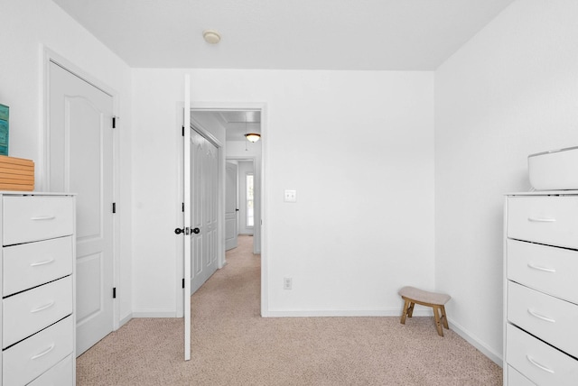 unfurnished bedroom with baseboards, light carpet, and attic access