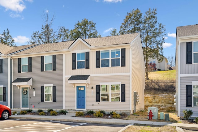 townhome / multi-family property with roof with shingles and uncovered parking