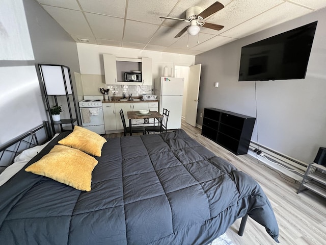 bedroom featuring a paneled ceiling, light wood-style floors, a ceiling fan, and freestanding refrigerator