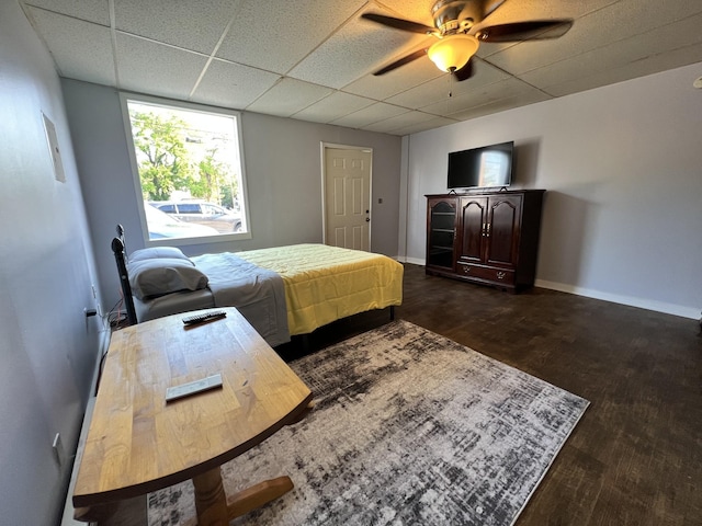 bedroom with a drop ceiling, a ceiling fan, baseboards, and dark wood-style flooring