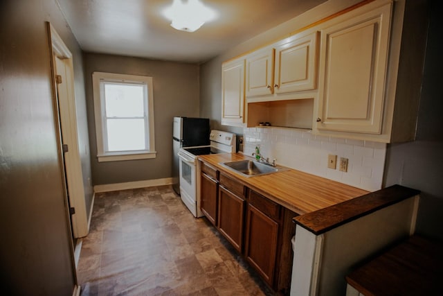 kitchen with baseboards, electric range, a sink, cream cabinetry, and tasteful backsplash