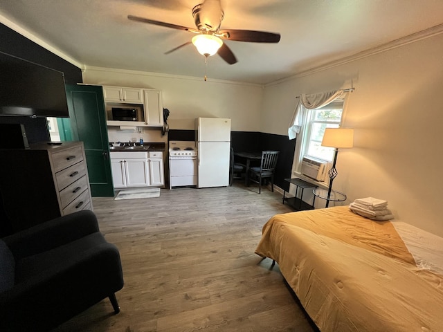 bedroom with ornamental molding, cooling unit, freestanding refrigerator, wood finished floors, and a sink