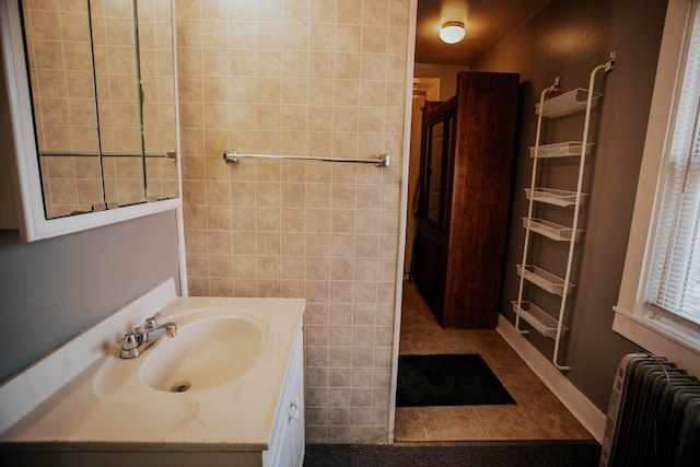 bathroom with tile patterned flooring, vanity, radiator heating unit, and tile walls