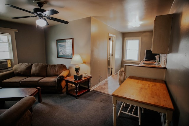 living room featuring carpet flooring, baseboards, and ceiling fan