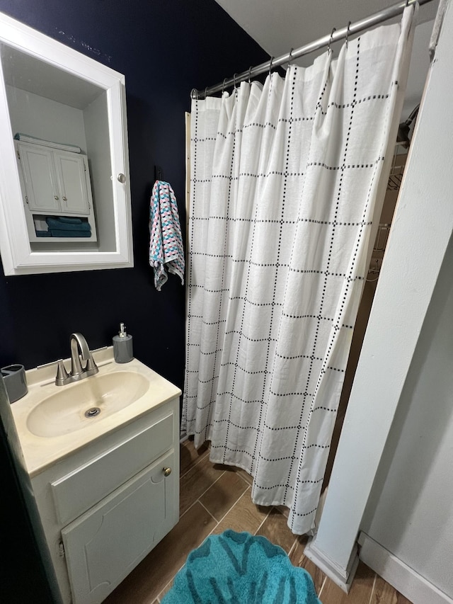 full bathroom featuring wood finish floors, curtained shower, baseboards, and vanity