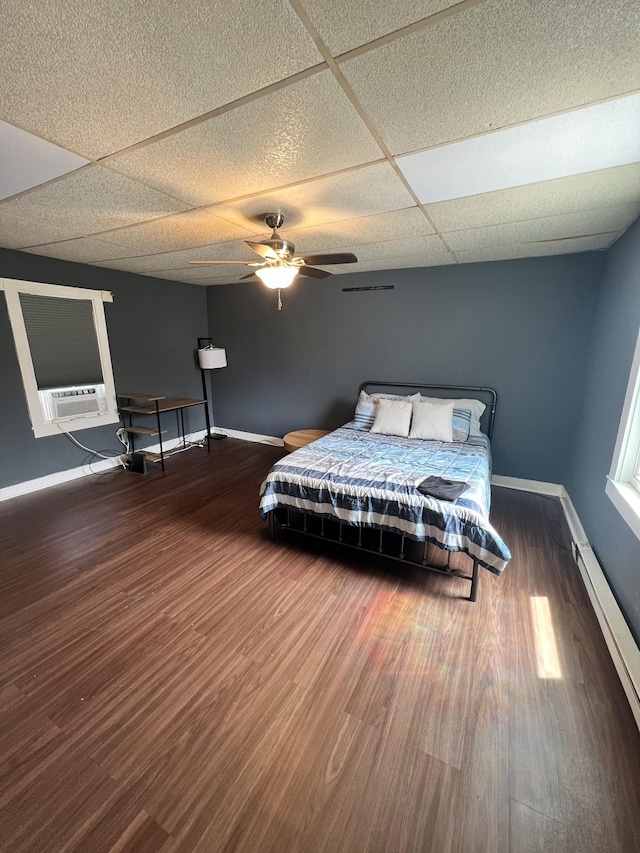 bedroom with cooling unit, a ceiling fan, wood finished floors, baseboards, and a paneled ceiling