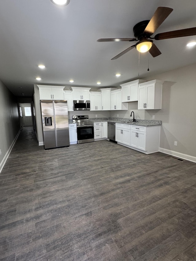 kitchen featuring dark wood finished floors, recessed lighting, white cabinets, stainless steel appliances, and a sink