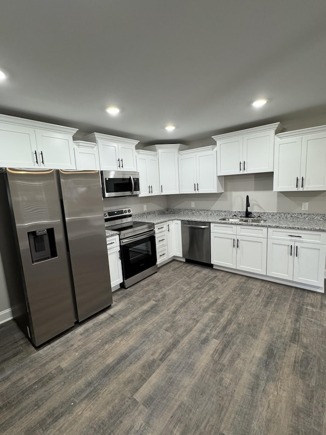 kitchen featuring dark wood-style flooring, white cabinetry, stainless steel appliances, and a sink