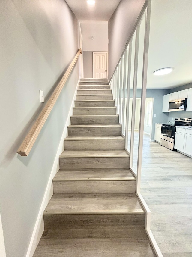 staircase with baseboards and wood finished floors