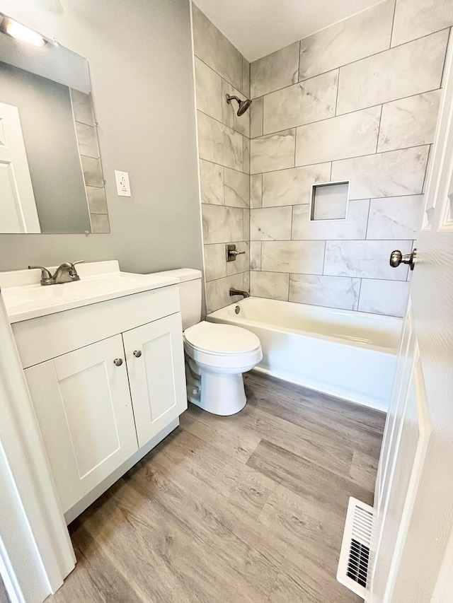 bathroom with vanity, wood finished floors, visible vents, bathtub / shower combination, and toilet