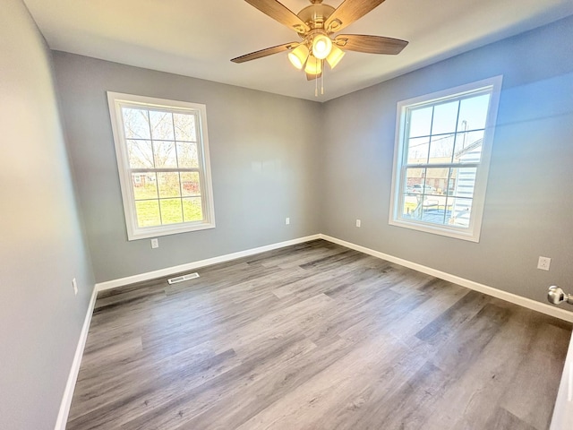 unfurnished room featuring visible vents, baseboards, wood finished floors, and a ceiling fan