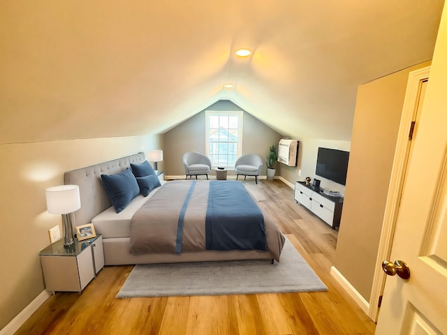 bedroom featuring baseboards, wood finished floors, and vaulted ceiling