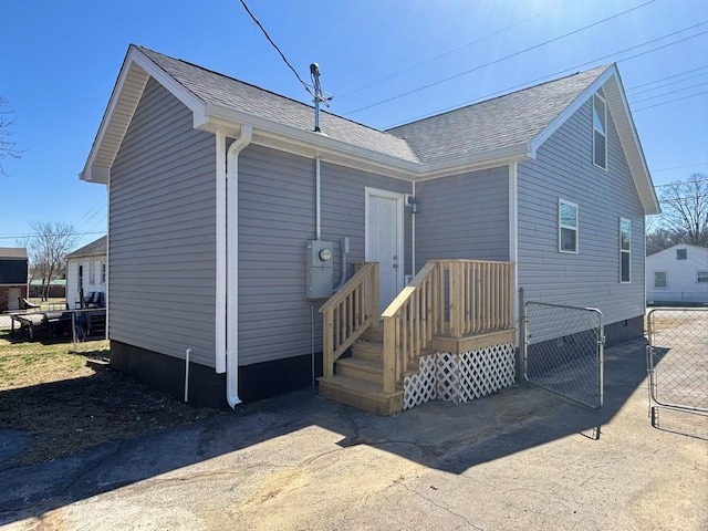 back of house with a gate, a shingled roof, and fence