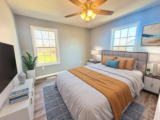 bedroom with ceiling fan, wood finished floors, visible vents, and baseboards