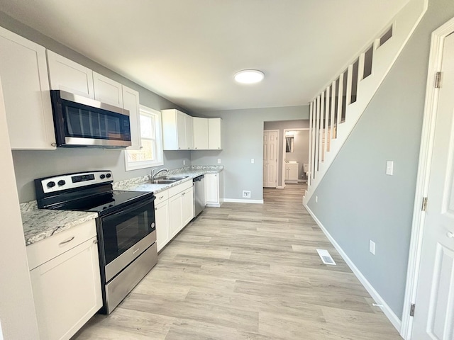 kitchen featuring baseboards, visible vents, a sink, appliances with stainless steel finishes, and white cabinetry