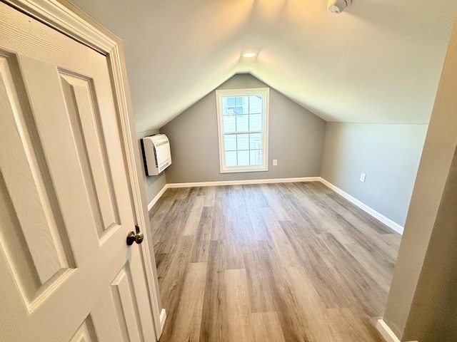 bonus room with lofted ceiling, heating unit, wood finished floors, and baseboards