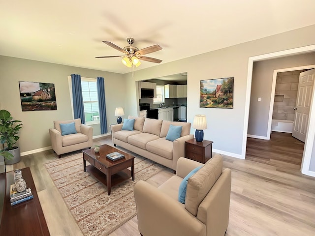 living room with baseboards, light wood finished floors, and ceiling fan