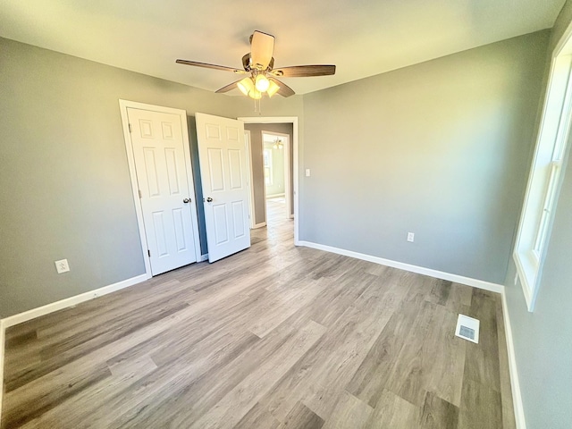 unfurnished bedroom featuring visible vents, ceiling fan, baseboards, and wood finished floors