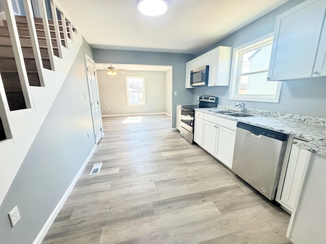 kitchen with visible vents, baseboards, light wood-style flooring, stainless steel appliances, and a sink