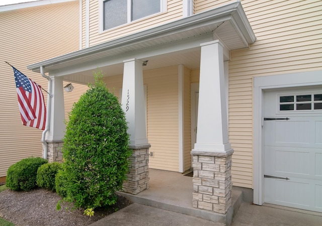 view of exterior entry featuring a garage, stone siding, and a porch