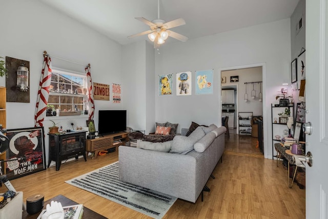 living area featuring light wood-style flooring, visible vents, and ceiling fan