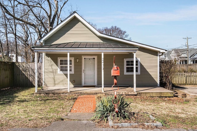 bungalow with a porch, metal roof, a standing seam roof, and fence