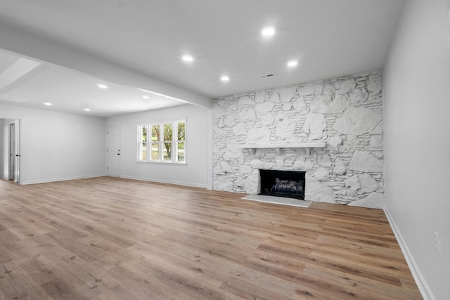 unfurnished living room featuring visible vents, baseboards, a stone fireplace, recessed lighting, and wood finished floors