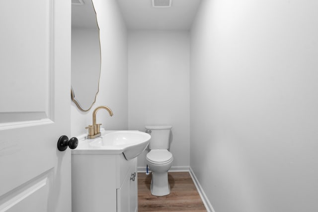 bathroom with vanity, wood finished floors, visible vents, baseboards, and toilet