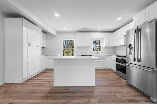 kitchen featuring light wood-type flooring, white cabinetry, appliances with stainless steel finishes, and light countertops