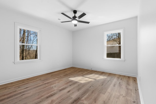 empty room with visible vents, baseboards, wood finished floors, and a ceiling fan