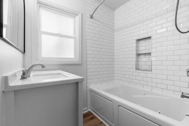 full bath featuring vanity, a combined bath / shower with jetted tub, and wood finished floors