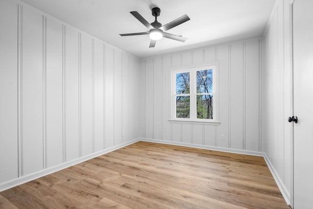 unfurnished room featuring light wood-style floors, a ceiling fan, and a decorative wall