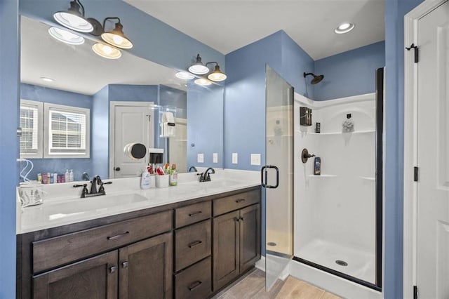 full bathroom with a shower stall, wood finished floors, double vanity, and a sink