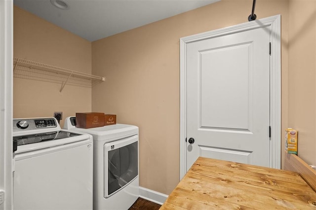 clothes washing area featuring baseboards, washing machine and dryer, and laundry area