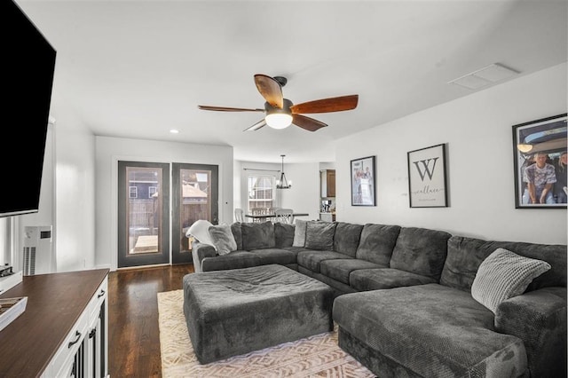 living room featuring ceiling fan with notable chandelier, recessed lighting, dark wood-style floors, and visible vents