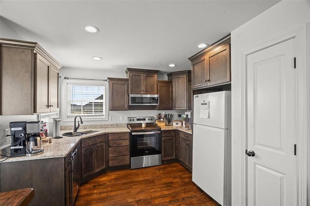 kitchen featuring light stone countertops, dark wood-style floors, a sink, dark brown cabinetry, and appliances with stainless steel finishes