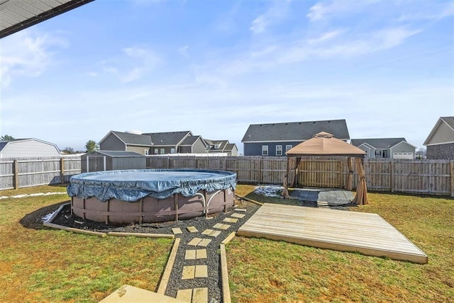 view of yard with a fenced in pool, a residential view, a gazebo, a fenced backyard, and a deck