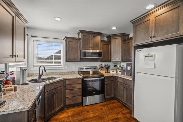 kitchen featuring dark brown cabinetry, appliances with stainless steel finishes, dark wood-type flooring, and a sink